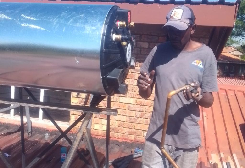 Technician installing an electric geyser on a rooftop