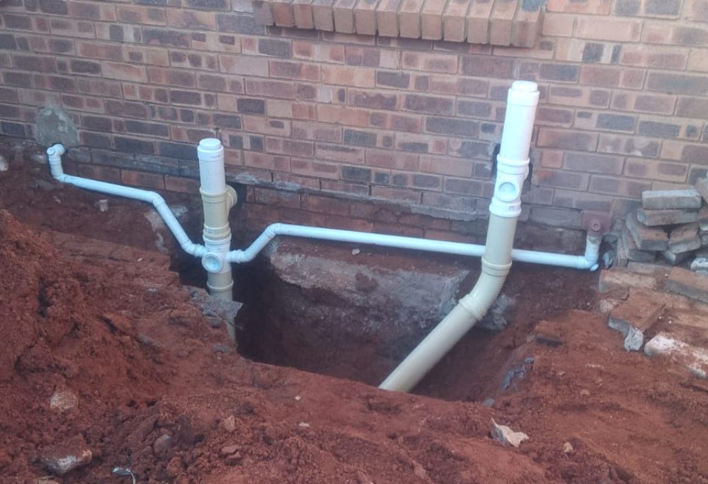 New plumbing installation with exposed pipes outside a building.