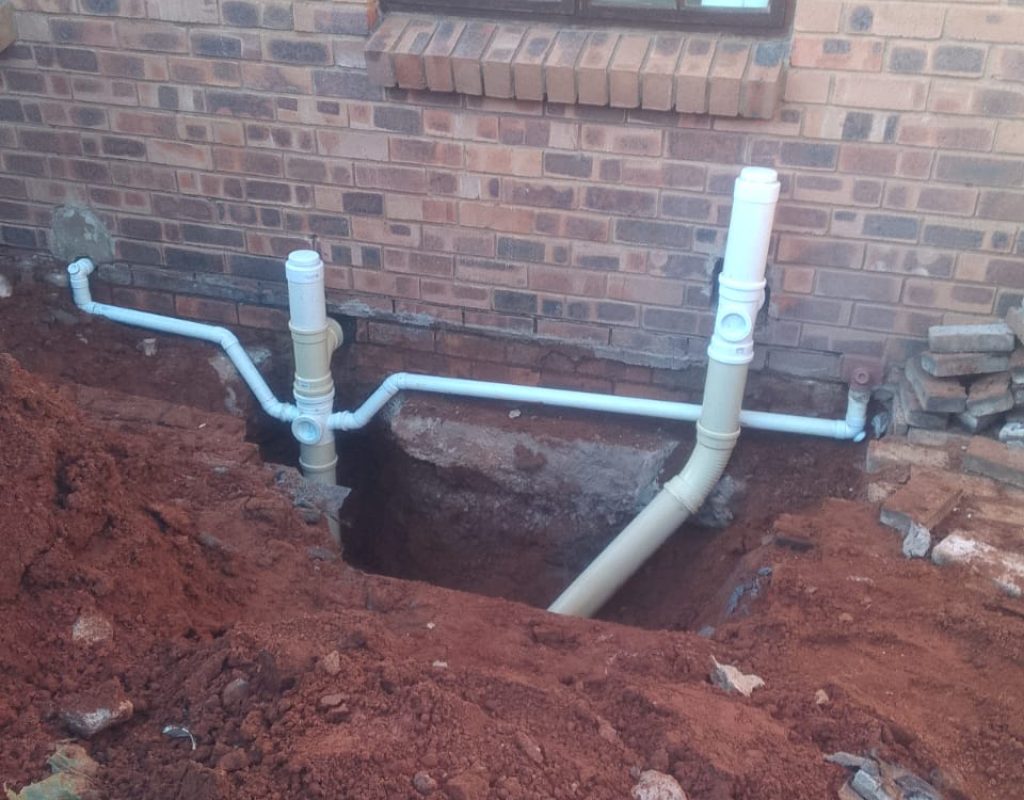 New plumbing installation with exposed pipes outside a building.